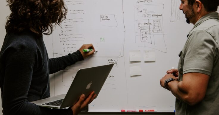 Photo by Kaleidico man wearing gray polo shirt beside dry-erase board